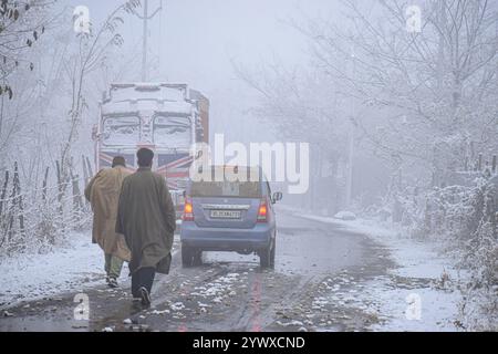 Srinagar, India. 12 dicembre 2024. La gente cammina in mezzo a nevicate fresche nel charar i Shareef del quartiere budgam il 12 dicembre 2024. (Foto di Danish Showkat /Sipa USA) credito: SIPA USA/Alamy Live News Foto Stock