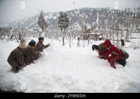 Srinagar, India. 12 dicembre 2024. Nevicate fresche a Heerpora Shopify nel sud del Kashmir. Le persone camminano mentre i ragazzi giocano con la neve dopo una nevicata fresca. (Foto di Nisar UL Haq Allaie/Pacific Press) credito: Pacific Press Media Production Corp./Alamy Live News Foto Stock