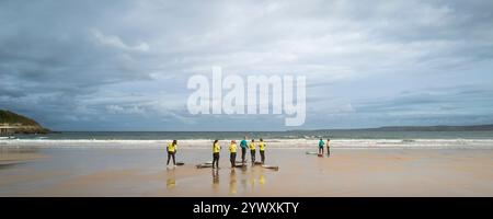 Un'immagine panoramica di un istruttore di surf della Escape Surf School con i suoi studenti principianti all'inizio di una lezione di surf a Towan Beac Foto Stock