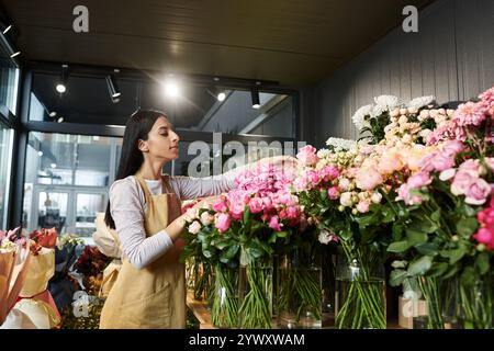 Una fiorista organizza fiori vivaci nel suo accogliente negozio, mostrando la sua passione. Foto Stock