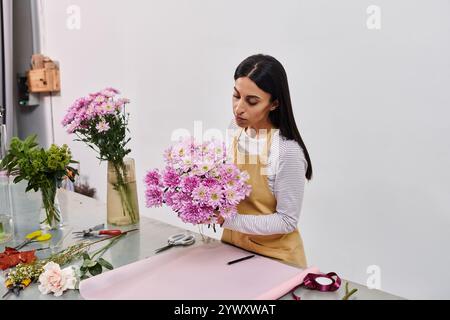 Una fiorista dedita organizza con cura un bellissimo mazzo di fiori, mettendo in mostra la sua creatività. Foto Stock