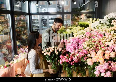 Una coppia di sposi organizza con gioia rose e piante bellissime nel loro negozio di fiori. Foto Stock