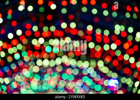 Immagine sfocata di un albero di Natale con luci verdi, rosse e blu. Le luci sono sparse su tutto l'albero, creando un'atmosfera festosa Foto Stock