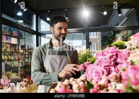 Il bell'uomo barbuto cura splendide composizioni floreali nel suo accogliente negozio. Foto Stock