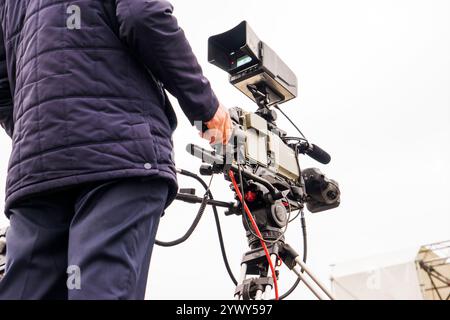 cameraman con la sua videocamera che gira all'aperto nel parco cittadino Foto Stock