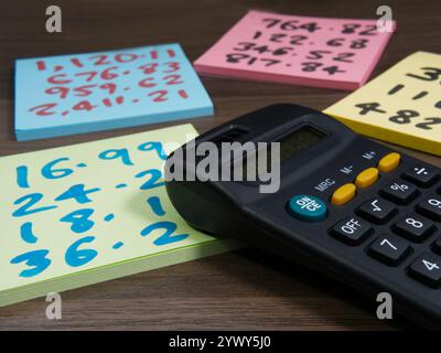 Primo piano di quattro blocchi appunti colorati con più figure scritte in feltro, accanto a una calcolatrice. Foto Stock