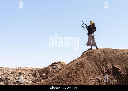 Guardia di sicurezza con il paesaggio vulcanico di Dallol sullo sfondo, Etiopia Foto Stock