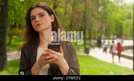 Triste arrabbiata irritata donna caucasica che guarda intorno ricerca aspetta tardi incontro utilizzando cellulare smartphone SMS inviare messaggio donna d'affari Foto Stock