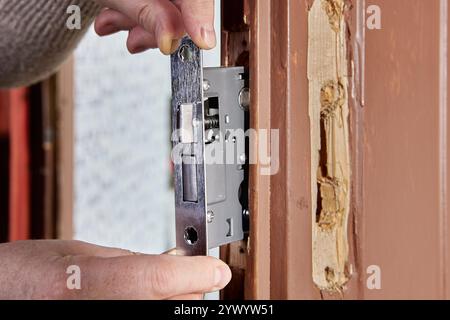 Il fabbro inserisce il telaio della porta a mortasa nella scanalatura o nella tasca tagliata sul bordo della porta. Foto Stock