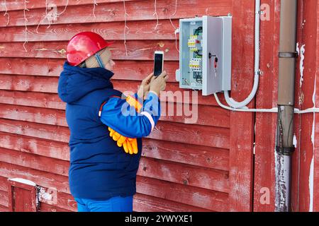 Scansione delle letture dei contatori elettrici, un ingegnere dell'azienda elettrica utilizza un dispositivo mobile. Foto Stock