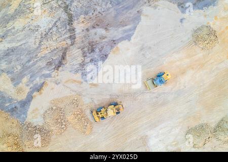 macchinari pesanti in un cantiere, un bulldozer e un rullo a vapore che preparano il terreno, vista aerea con drone Foto Stock