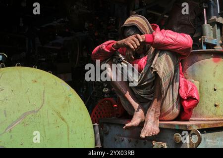 Un anziano lavoratore del cantiere che si immerge nel calore del sole del mattino d'inverno. Foto Stock