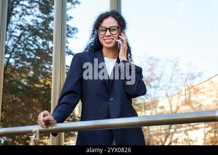 Ritratto di una giovane donna in abito elegante che parla al telefono all'aperto Foto Stock