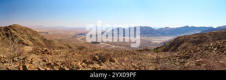 Un magnifico panorama grandangolare cattura una strada di montagna sterrata tortuosa che si snoda attraverso le vaste valli aride sotto il passo di Spreetshoogte, in Namibia. Foto Stock