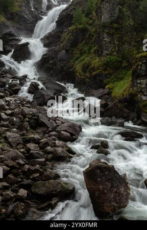 Una splendida cascata scorre attraverso una lussureggiante foresta, che crolla sulle rocce e circondata da una vegetazione vivace. Il rumore dell'acqua che scorre si fonde con il p Foto Stock