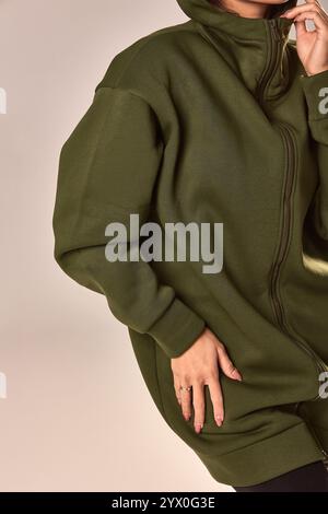Donna elegantemente vestita con cappuccio verde, sfoggia moda casual, abbigliamento elegante, capispalla caldo e abbigliamento moderno. Concetto di moda Foto Stock