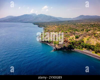 Vista aerea delle spiagge vulcaniche nere e della lussureggiante vegetazione tropicale di Bali, Indonesia Foto Stock