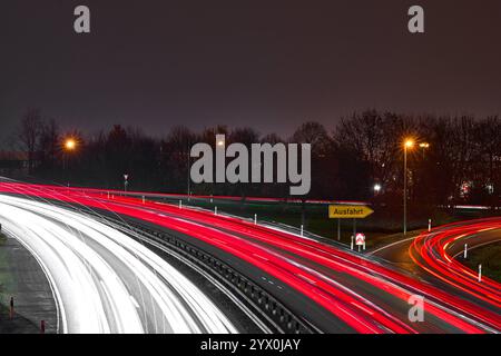 Baviera, Germania - 12 dicembre 2024: Immagine simbolica del traffico notturno: Un'uscita autostradale con corsie a luce rossa e bianca mostra dinamismo, mobilità e velocità. La lunga esposizione enfatizza il movimento dei veicoli e rappresenta l'infrastruttura moderna e l'orientamento nel traffico automobilistico. *** Symbolbild für nächtlichen Verkehr: Eine Autobahn-Ausfahrt mit roten und Weißen Lichtspuren zeigt Dynamik, Mobilität und Geschwindigkeit. Die Langzeitbelichtung hebt die Bewegung der Fahrzeuge hervor und steht für moderne Infrastruktur und Orientierung im Straßenverkehr von Autos. Foto Stock