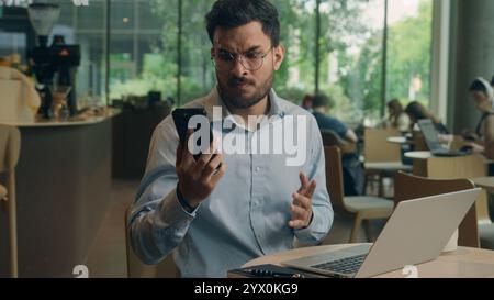 Uomo arabo ragazzo etnico turbato preoccupato frustrato uomo d'affari affari uomo datore di lavoro lavoro lavoratore libero professionista visitatore che legge schermo del telefono cellulare ricevere male Foto Stock