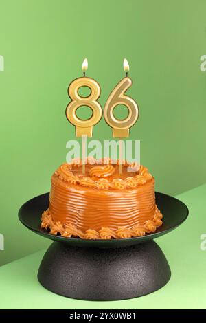 Deliziosa torta con dulce de leche - candela di compleanno numero 86 su sfondo verde. Foto Stock