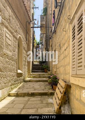 Korcula, Croazia - 30 giugno 2024: Guarda da ovest verso la strada, vicolo con scalini chiamato Vinka Foretica. Lavanderia colorata sul balcone, vasi di fiori Foto Stock