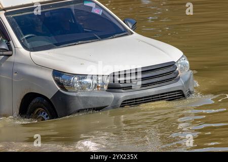 Un'auto attraversa una strada allagata della città Foto Stock