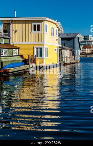 Una fila di case gialle e blu siedono su un corpo d'acqua. L'acqua è calma e le case si riflettono nell'acqua Foto Stock