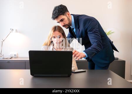 Colleghi che collaborano con un notebook in un ambiente Bright Office Foto Stock