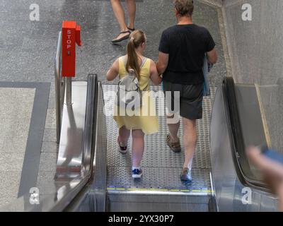 Padre con la bambina con la sindrome di Down che scende l'escalator. Foto Stock