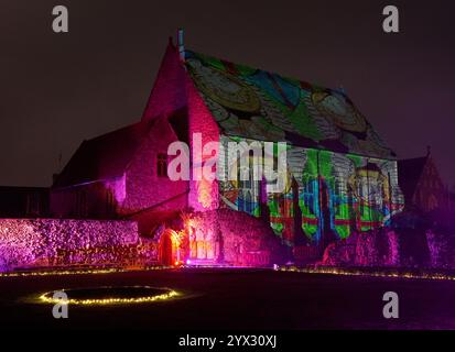 Una vista di fantastici racconti e dove trovarli, un'installazione di luci e suoni di Luxmuralis proiettata sulle rovine storiche dell'Abbazia di St Augustine e della King's School di Canterbury, Kent, che fa parte del Canterbury Arts Festival. Lo spettacolo è stato creato dalla pluripremiata collaborazione artistica dello scultore Peter Walker e del compositore David Harper. Data foto: Giovedì 12 dicembre 2024. Foto Stock