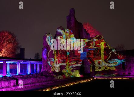Una vista di fantastici racconti e dove trovarli, un'installazione di luci e suoni di Luxmuralis proiettata sulle rovine storiche dell'Abbazia di St Augustine e della King's School di Canterbury, Kent, che fa parte del Canterbury Arts Festival. Lo spettacolo è stato creato dalla pluripremiata collaborazione artistica dello scultore Peter Walker e del compositore David Harper. Data foto: Giovedì 12 dicembre 2024. Foto Stock