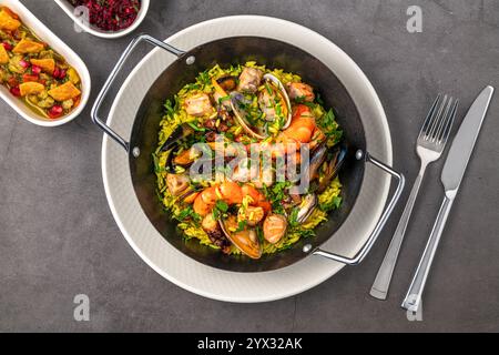 Vista dall'alto della tradizionale paella di pesce spagnola con riso, cozze e gamberi in una padella su un tavolo di legno Foto Stock