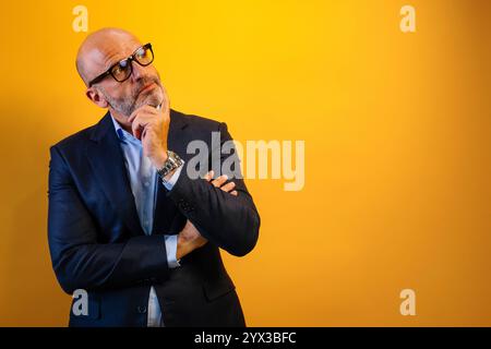 Un uomo con la barba e un vestito blu sta pensando. Sta guardando il lato destro della cornice, con un'espressione premurosa sul viso. Foto Stock