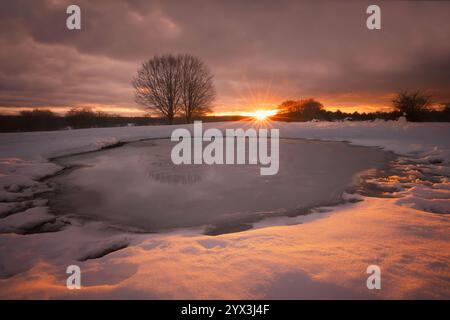 Alba invernale su un lago innevato Foto Stock