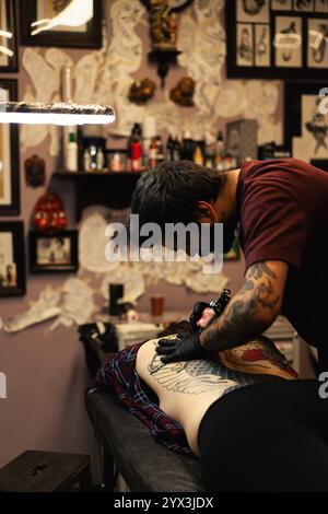 Tatuatore che fa tatuaggio tradizionale giapponese sulla schiena della donna Foto Stock