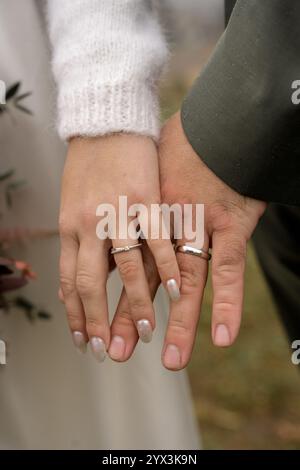 Coppia di sposi che si tiene per mano e indossa fedi nuziali Foto Stock