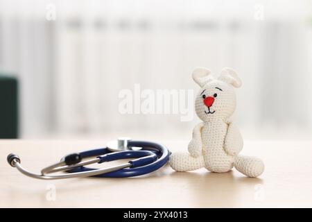 Concetto pediatrico. Coniglietto giocattolo con stetoscopio sul tavolo all'interno Foto Stock