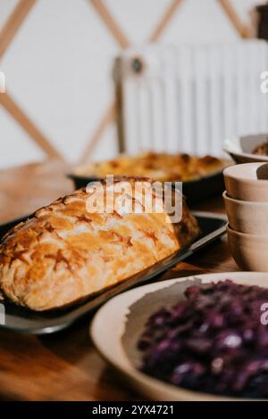 Un tavolo con una grande pagnotta di pane e molti altri piatti. Il pane è il punto focale principale dell'immagine ed è un pasto delizioso e invitante. L'ot Foto Stock