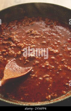 Cottura, salsa alla bolognese, in una padella, mescolando con un cucchiaio di legno, salsa di pomodoro, fatta in casa, nessuno Foto Stock