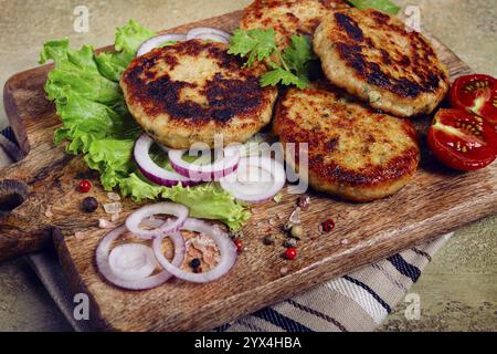 Cotolette di pollo fritte, pollo tritato, con verdure, su un tagliere, con insalata di verdure, vista dall'alto, fatti in casa, nessuno Foto Stock