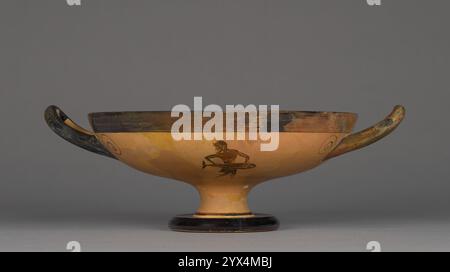 Kylix a figura nera dell'attico, circa 525-500 a.C. Bicchiere di vino con un pescivendolo. Ulteriori informazioni: Questa cilix ateniese a figura nera o coppa raffigura un mercato del pesce. Da un lato, un pescivendolo prepara un tonno in vendita. Sta per ritagliare il pesce su un blocco di triturazione. I pezzi già tagliati da un altro pesce giacciono sul tavolo dietro di lui e una testa di pesce riposa ai suoi piedi. Dall'altra parte, un altro uomo porta un tonno, forse appena pescato. Data la vasta costa della Grecia, i pesci erano importanti nella dieta greca, ma le raffigurazioni della pesca e della vendita di pesce sono rare nell'arte greca. Foto Stock