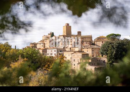 Vista da cartolina del villaggio collinare di Petroio attraverso i rami di cipressi in Toscana, Italia. Foto Stock