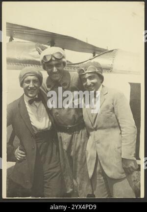 Ritratto di gruppo, 1915-1930. Ritratto di gruppo di tre uomini davanti a un aereo. Tutti e tre indossano berretti in maglia, due hanno gli occhiali da pilota sopra la testa. Il terzo uomo indossa una cravatta. Foto Stock