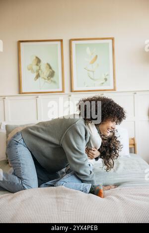 Un momento di gioia tra una madre e il suo bambino che abbracciano e giocano insieme su un letto in una camera accogliente. Foto Stock