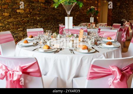 Elegante tavolo da nozze con nastri rosa e centrotavola floreale Foto Stock