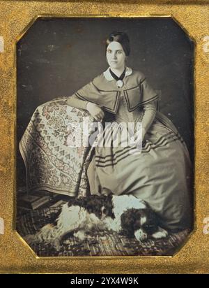 Ritratto di una giovane donna seduta e cane, 1845-1847. Ulteriori informazioni: Il cane fedele in questa immagine, dormendo sonni seri sul tappeto a motivi geometrici, era un accessorio insolito per una donna, poiché i cani erano tipicamente associati agli uomini. Tuttavia, l'animale domestico si annida contro la gonna del suo proprietario, sentendosi chiaramente a suo agio abbastanza da fare un pisolino durante la lunga esposizione. Un panno a motivo di ammassi d'uva e edera, su cui la donna poggia il braccio, bilancia la composizione triangolare. Foto Stock