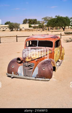 Un vecchio temporizzatore arrugginito, un'auto con orrange e parti di colore giallo, senza finestrini o pneumatici, relitti di auto di Solitare, Namibia Foto Stock
