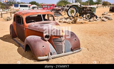Un vecchio temporizzatore arrugginito, un'auto con orrange e parti di colore giallo, senza finestrini o pneumatici, relitti di auto di Solitare, Namibia Foto Stock