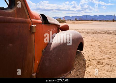 Un vecchio temporizzatore arrugginito, un'auto con orrange e parti di colore giallo, senza finestrini o pneumatici, relitti di auto di Solitare, Namibia Foto Stock