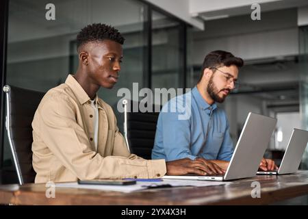 Due dipendenti di aziende di sesso maschile che utilizzano laptop che lavorano in ufficio. Foto Stock